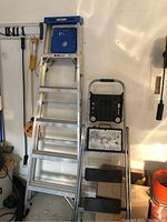Full view of the Werner aluminum ladder with blue plastic tool tray on left, Skinny Mini multi step stool on right.