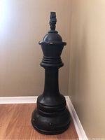 Front-left angle view of the large black chess king piece statue showing height and structural details.