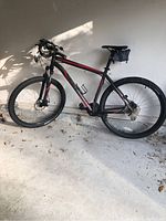 Full side view of mountain bike showing handlebar-mounted LED light, water bottle cage, frame, wheels, and saddle