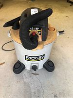 Full view of the Ridgid shop vac showing body, caster wheels, hose, and part of the power cord.