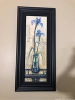 Full view of rectangular framed flower painting on wall showing design and frame.