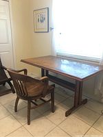 Desk and chair positioned by window on tiled floor, showing overall condition and wear.