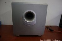 Front view of grey JBL SUB 180 subwoofer showing circular bass port and JBL logo.
