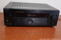 Front view of Sony STR-DEN75 receiver powered on, displaying '2CH STEREO'. Shows main control panel with volume knob, input buttons, headphone jack, and digital display.