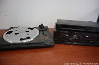 Three Technics audio components arranged on a table: turntable on left, cassette deck and tuner stacked on right.