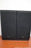 Pair of Technics SB-A10 speakers front view, black fabric covers, slight damage and speckling on fabric noted, logos visible.