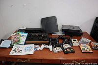 Overhead view of all items arranged on a table including Atari 2600, PS2, Game Boys, controllers, cartridges and game discs