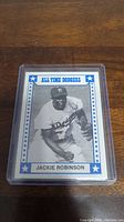 Front view of 1980 TCMA Jackie Robinson baseball card in protective sleeve, showing Jackie Robinson in Dodgers uniform with blue and white frame and 'All Time Dodgers' label.