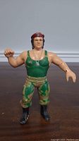 Front view of the LJN Corporal Kirchner action figure showcasing the green mesh tank top, camouflage pants, black boots, red beret, and dog tags.