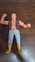 Front view of LJN Outback Jack action figure showing the character's flexed arm, brown vest, light blue pants, and yellow boots.