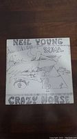 Front cover of the vinyl record album "Zuma" by Neil Young & Crazy Horse featuring black and white hand-drawn artwork with desert and bird illustrations and text.