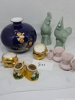 Wide view of entire lot including vase, rooster figurines, salt cellars, and ceramic mugs