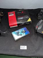 Zenith DTT901 digital TV tuner converter box in its original box with red and black colors, alongside a USB mini fan in sealed packaging on a black surface.