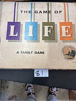 Top of The Game of Life box with colorful letters and seal