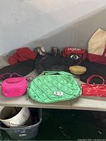 Table with eight assorted handbags and purses in different colors and materials.