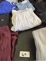 Top down photo of assortment of jeans and jogging pants displaying different items in the lot