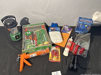 Photo showing all items in lot including lantern, painting set, garden tools, caulking gun, adhesive, torch, and gloves.