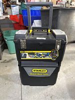 Closed Stanley Mobile Work Center toolbox on wheels showing brand and labeled compartments.