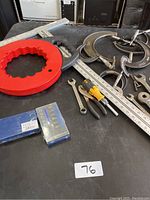 Overall view of assorted hand tools including wrenches, pliers, rulers, and a red plastic ring tool