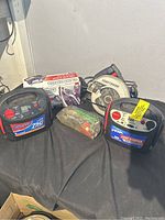 Overall view showing two jump starters, Craftsman saw, boxed Black+Decker iron, small bag of parts