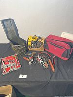 Overview of all tools displayed on black cloth: drill, wrenches, hand tools, tool bag, ammo box
