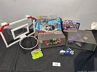 Mixed lot including new red and white basketball hoop with net attached. Several boxed and loose model cars and toys on black cloth.