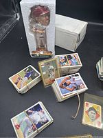 Photo showing Mike Schmidt bobblehead in styrofoam packaging with white box behind it, multiple stacks of baseball cards on the table
