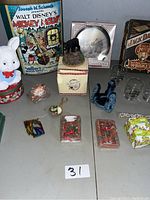 Photo showing the full assortment of vintage items including the Disney tin, bunny figurine, small clock, black bear figurine, wax figures, and glasses.