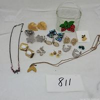 Overview of all jewelry items and glass basket in the lot spread on a white surface