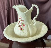 Ivory ceramic wash pan and matching pitcher displayed together showing floral designs and embossed patterns