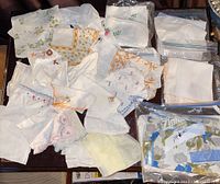 Box contents showing various vintage table napkins, handkerchiefs, and aprons laid out on a surface, some in plastic bags.