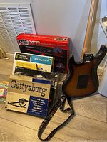Electric guitar, Gettysburg game, Ice Mummy kit, Tyco XDG box, and other items on floor