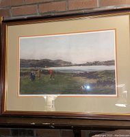 Framed engraving showing three golfers on a green near water and hills in background, matted and framed in wood frame with gold trim.