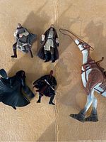 Five Star Wars action figures displayed on tan surface: two versions of Obi-Wan Kenobi, Darth Maul, dark cloaked figure, and large creature with saddle and reins.