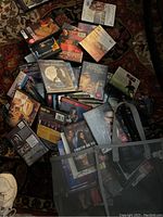 Loose DVDs scattered on carpet showing multiple movie titles in standard and slim DVD cases