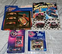 Photo showing multiple NASCAR Matchbox cars in original blister packaging laid out on surface with clear labels of Winner's Circle and Daytona 500 series.