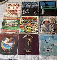 Nine rock and roll vinyl albums arranged in a 3x3 grid, showing front covers including Wings, Fine Young Cannibals, Hall & Oates, Steve Miller Band, Big Brother and the Holding Company with Janis Joplin, The Band, Boz Skaggs, Simon & Garfunkel, and Elton John.
