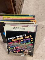 Photo showing a side view of several vinyl records stacked together, visible titles include Chuck Berry's Golden Hits and The Everly Brothers' Original Greatest Hits.