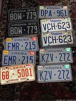 Photo showing eight vintage license plates arranged in groups. Includes black Virginia plates from 1972, white Virginia plates from 1978, 1982, 1985, and Florida plate from 1975.