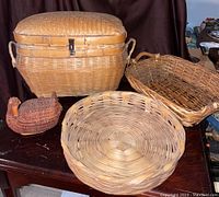 Four vintage baskets displayed on a table: large picnic basket, swan-shaped basket, oval and round trays.