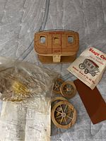 Wooden model pieces with wheels, instruction sheet, and partial original packaging