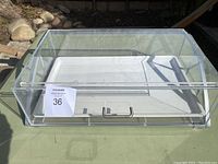 Front view of Hubert acrylic bakery display case showing clear acrylic drawer with metal handle attached to metal base.