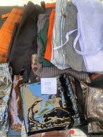 Collection of cotton and vinyl aprons, assorted colors and styles including orange, black, grey, white, striped, green, and shiny black vinyl apron, with vinyl sleeve protectors included.