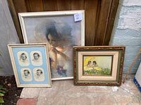 Three framed artworks shown outside leaning against wall, includes baby pictures, Pat Kennerty painting and large woman print.