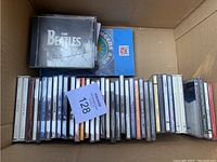 Box containing multiple CD jewel cases with titles including The Beatles and Time Life set.