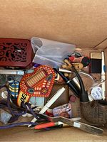 Box of various small collectibles including pipes, pens, patches, and a wooden heart-shaped item