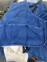 Close-up of blue denim apron with front pocket and visible buckle strap