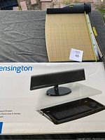 Swingline classic cut paper cutter showing wooden base with grid and cutting blade, placed on top of Kensington keyboard drawer box
