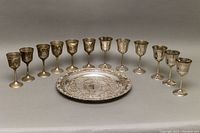 Full set of 12 goblets arranged in a row with serving tray in front, showing size and condition differences