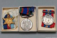 Three military medals displayed in their boxes: King George VI 2-inch medals including the WWII 1939-1945 medal and the Canadian Voluntary Service Star medal with Royal Cypher and star shape